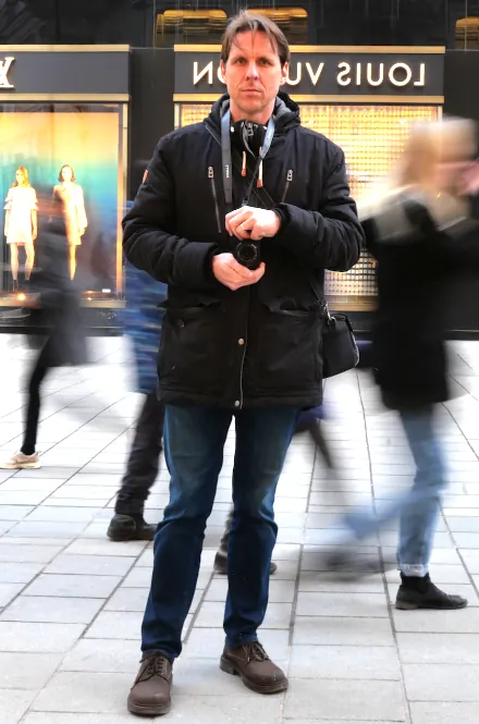 Mario mit Kamera vor Spiegel. Fu&szlig;g&auml;ngerzone mit Bewegungsunsch&auml;rfe im Hintergrund.